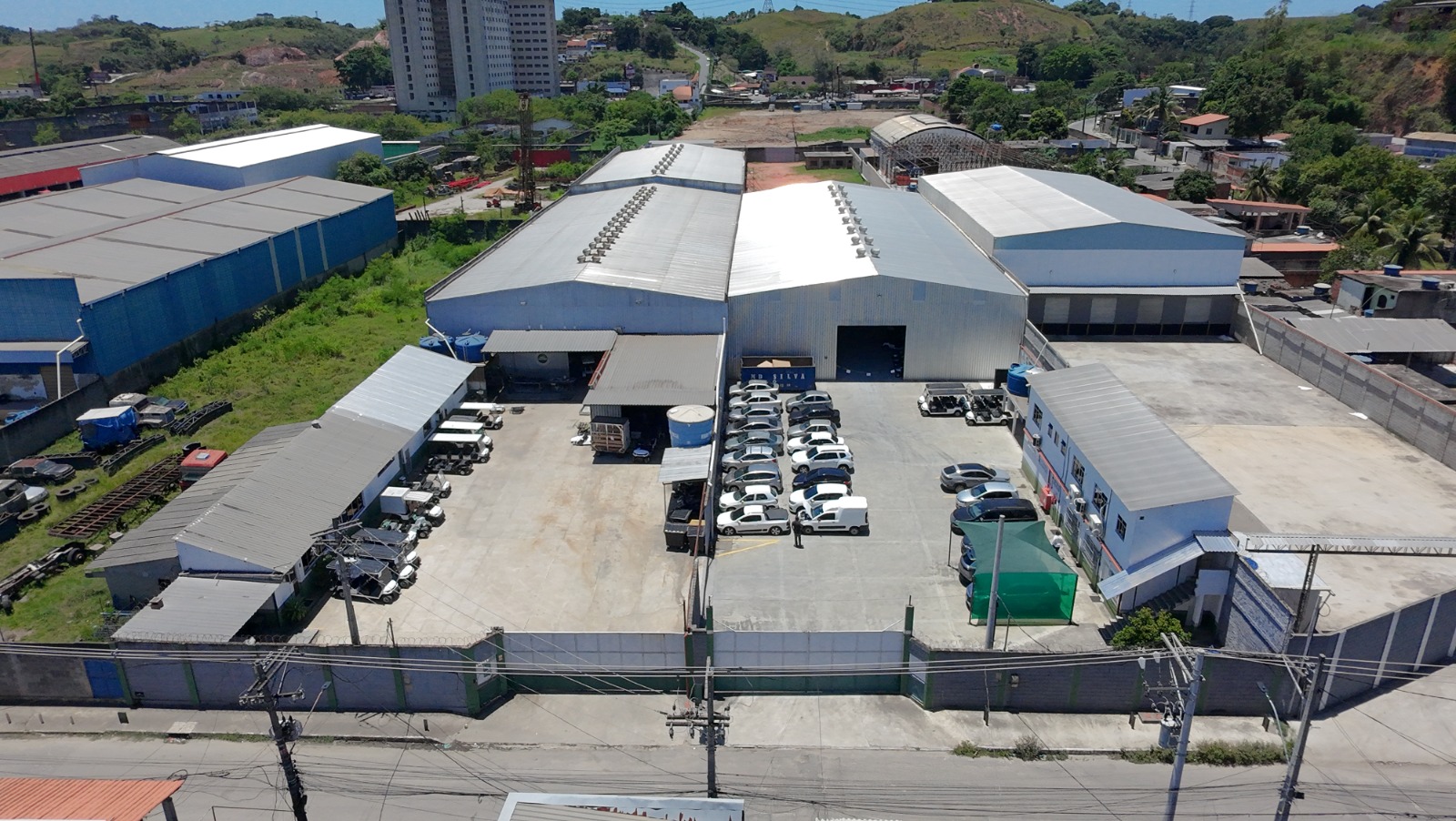 Vista aérea da matriz da Car Station no Rio de Janeiro, com galpões industriais e frota de carrinhos no pátio